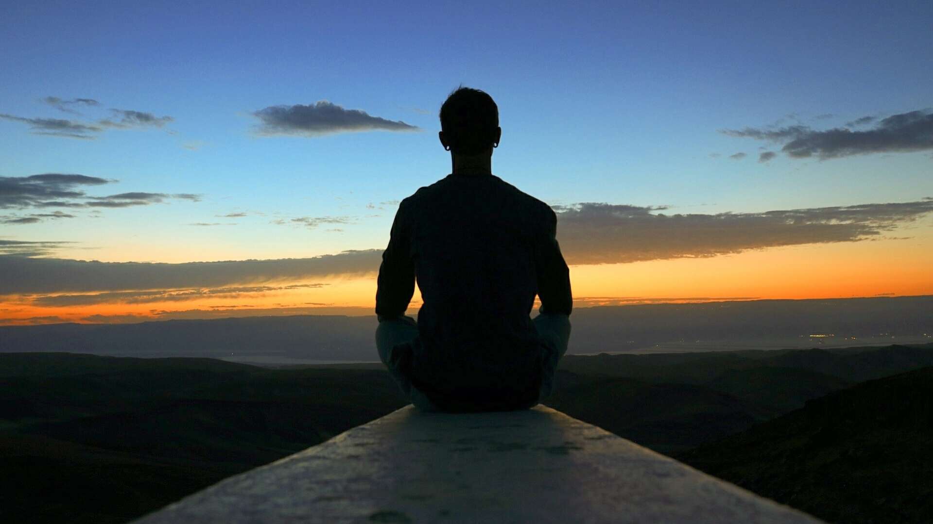 Person meditating in silence at sunrise, symbolizing mindfulness and reflection for legal professionals.
