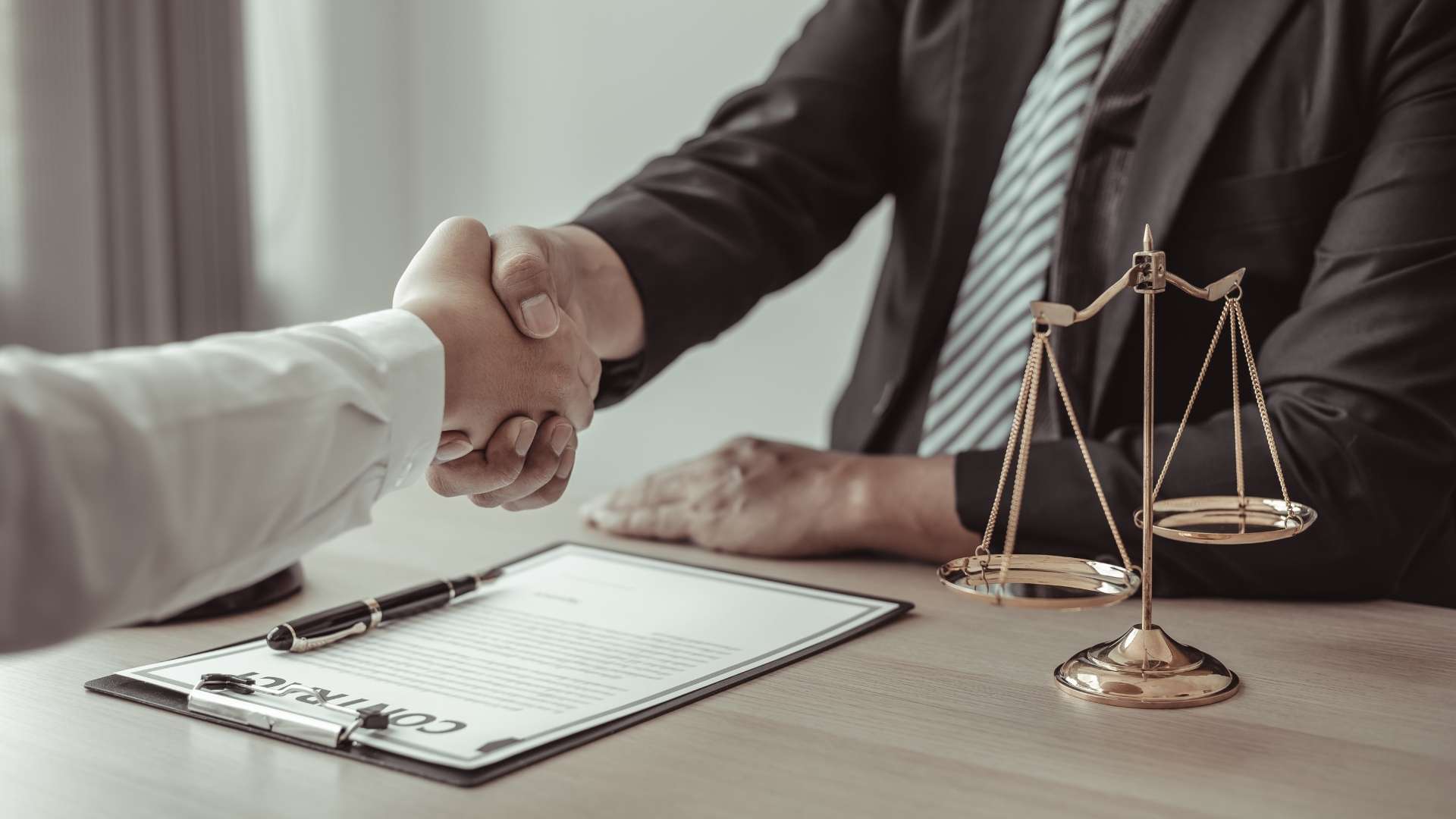 Two professionals shaking hands over a legal contract, symbolizing resolution of trademark concerns with legal support in Los Angeles.