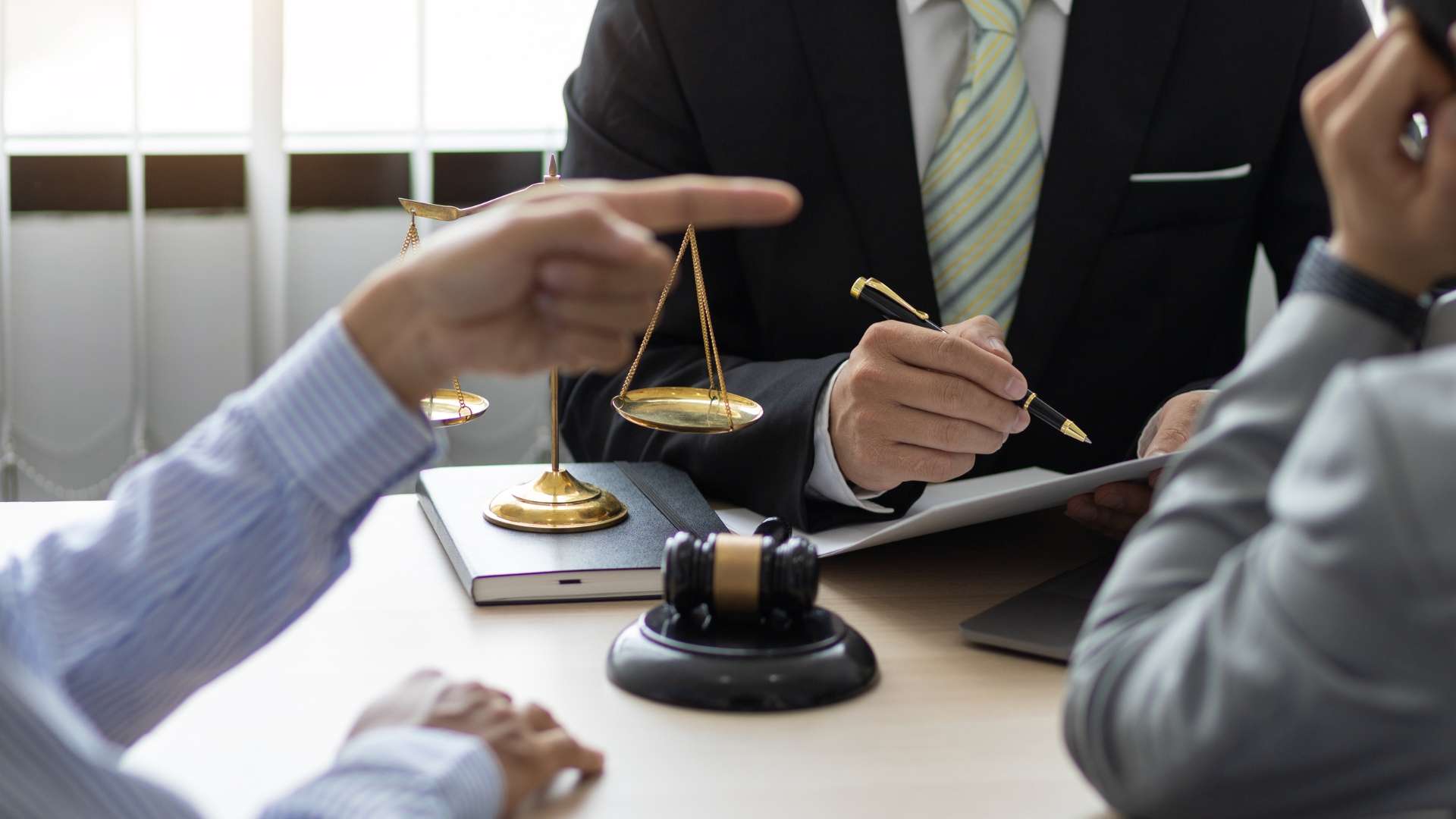 Legal consultation with scales of justice and gavel on table, attorneys discussing contract issues, Los Angeles business law setting.