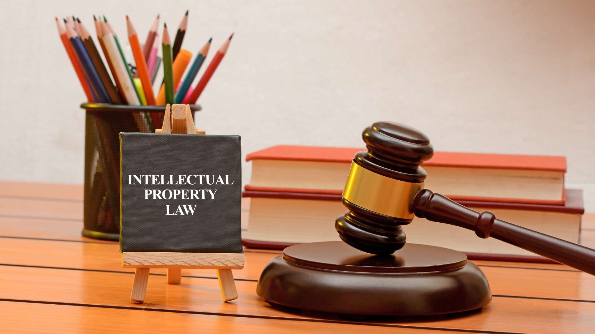 Desk with gavel, books, colored pencils, and a sign reading "INTELLECTUAL PROPERTY LAW" symbolizing legal protection of creative works.