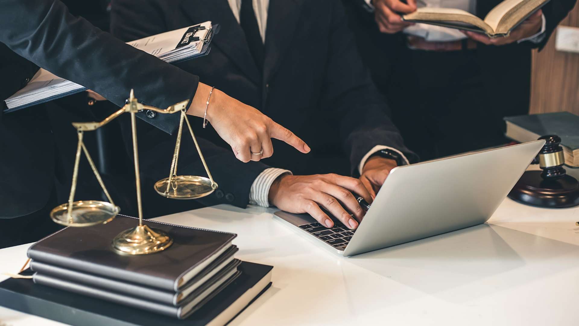 Business attorneys reviewing employment contracts on a laptop during a business acquisition.