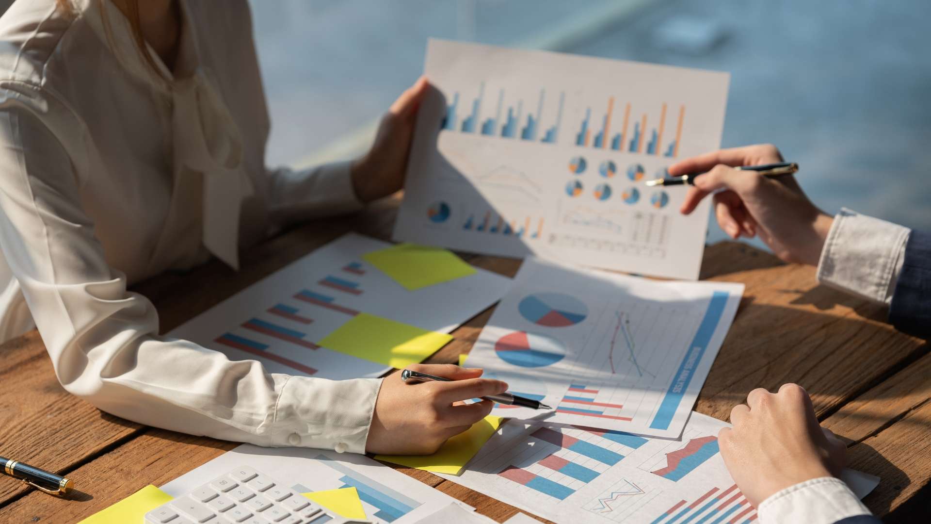 Two business professionals analyzing marketing charts and legal growth metrics on a wooden desk.
