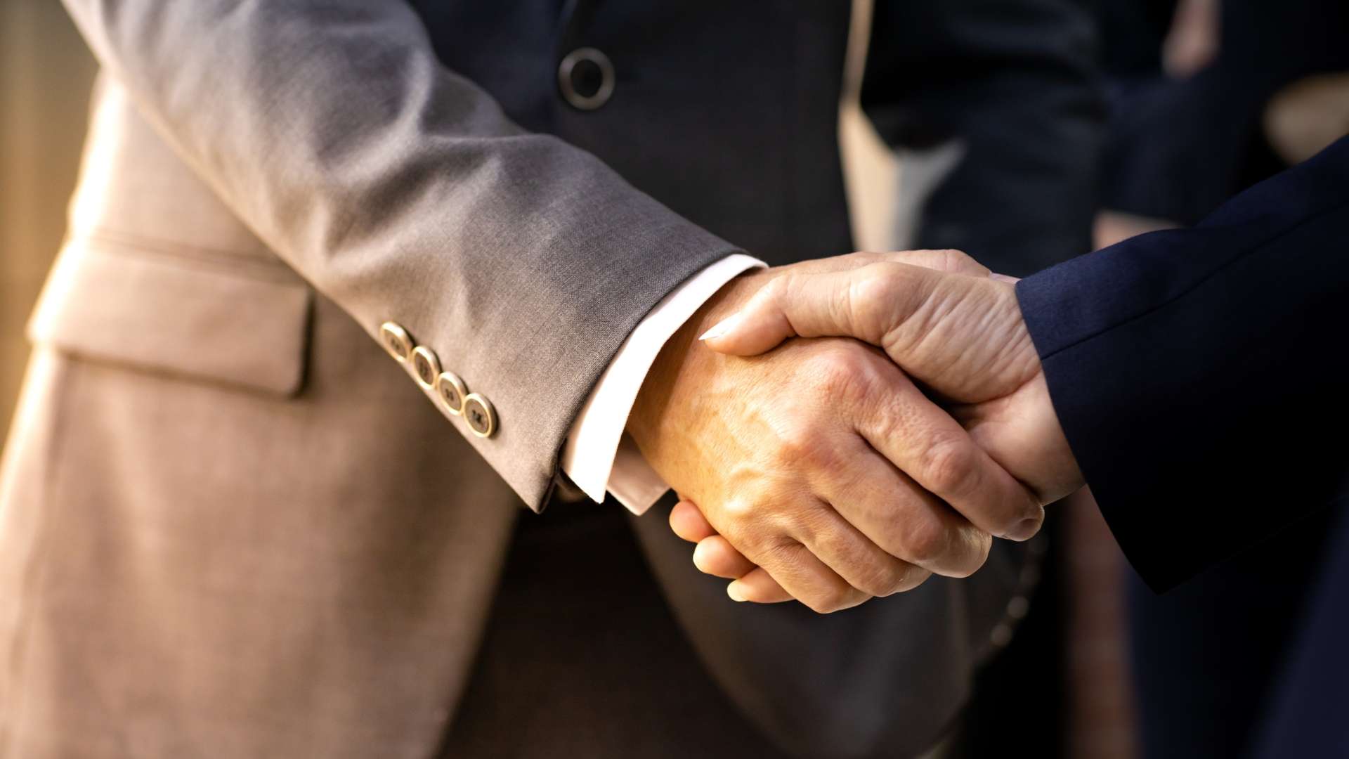 A faceless professional signs contracts for a business acquisition, supported by Carbon Law Group, with an LA skyline at dusk.