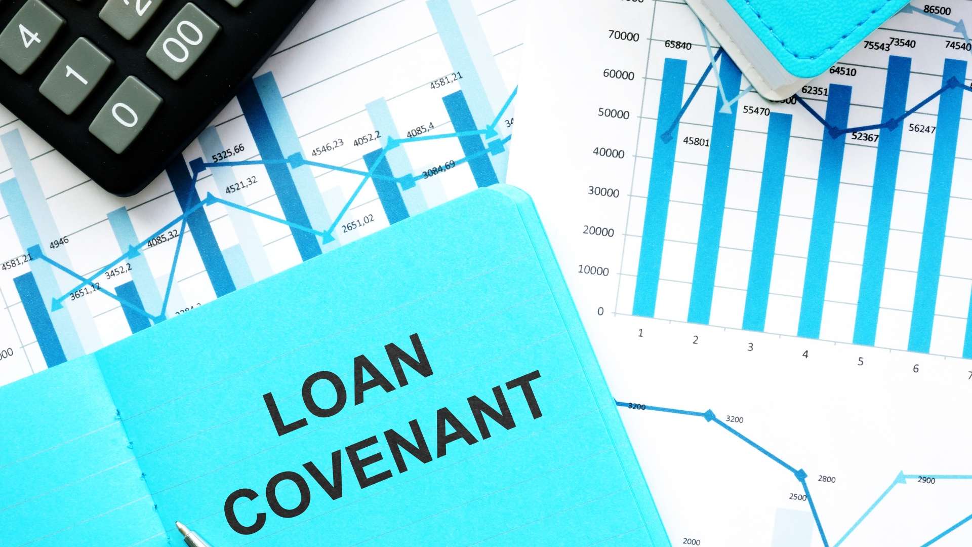 Blue folder labeled “Loan Covenant” placed on financial charts and graphs, symbolizing hidden risks in business loan agreements.