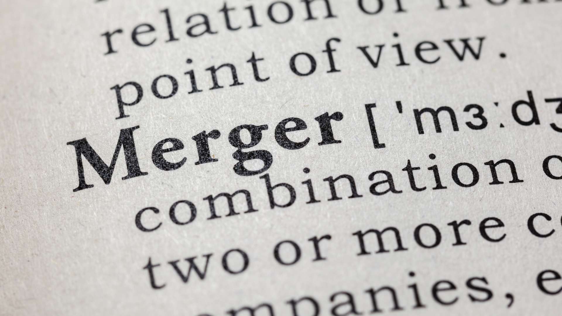 Close-up of the word “merger” highlighted in a dictionary, symbolizing business consolidation and acquisition strategy.