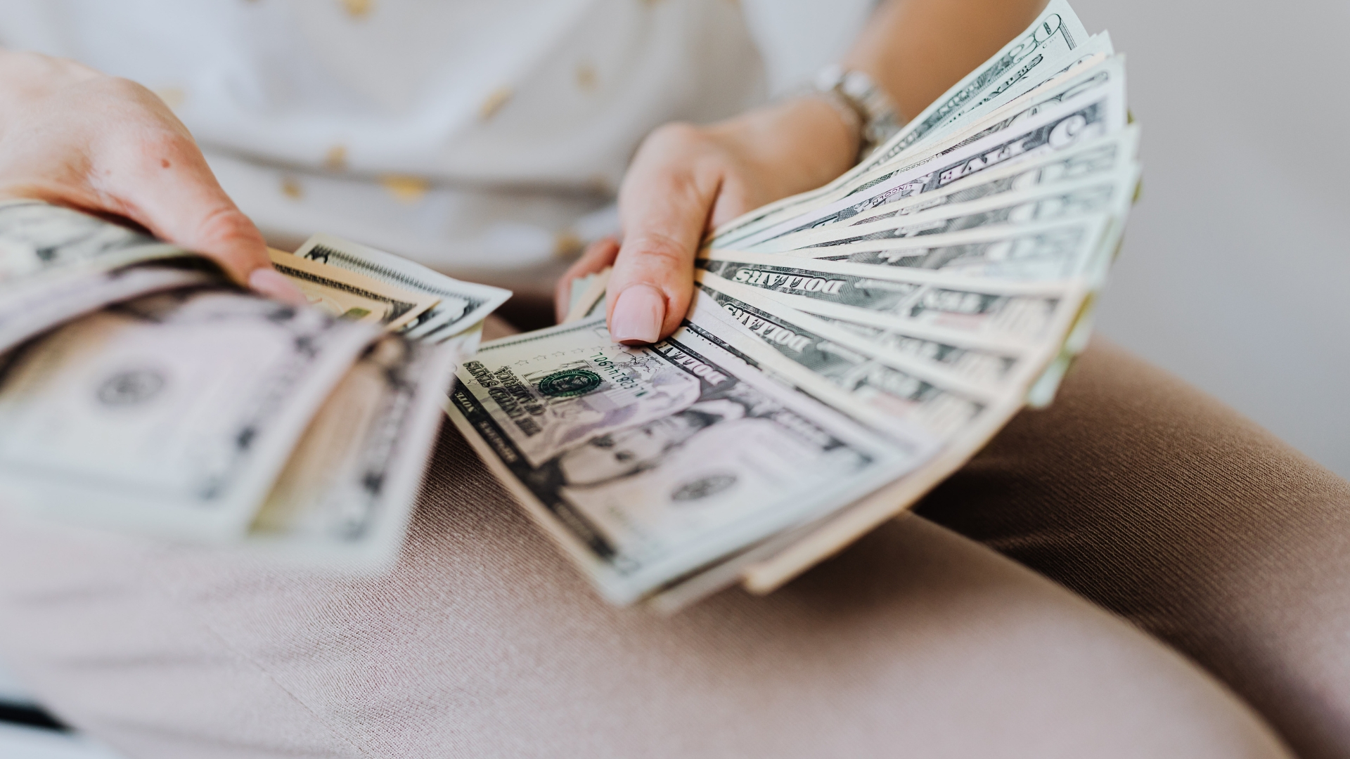 Person counting U.S. dollar bills representing financial growth and equity incentives for LLC employees