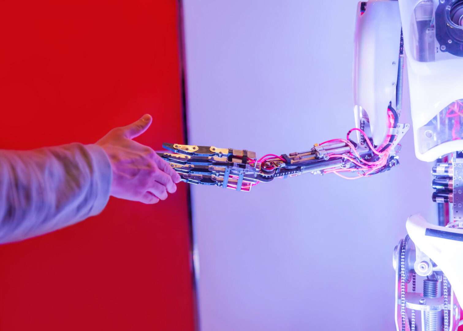 A human hand reaching out to shake the mechanical hand of a robot, symbolizing the intersection of human business decisions and AI technology at the center of the Musk vs. Altman OpenAI trial.