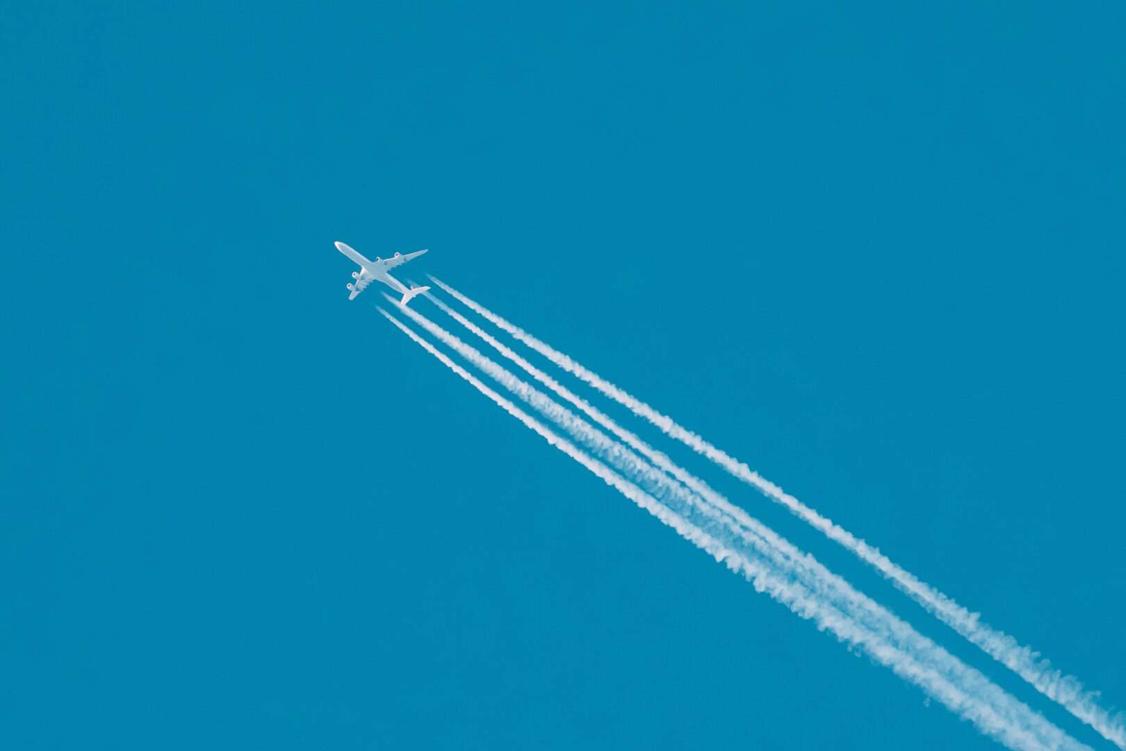 A commercial airplane flying through a clear blue sky with white contrails trailing behind it, representing the rise and fall of Spirit Airlines and the business formation and liability lessons every small business owner must learn.