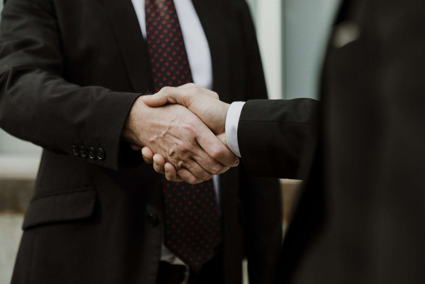 Two business professionals in suits shaking hands in an urban setting, representing the trusted legal partnership that a monthly retainer with a business lawyer in Los Angeles provides for small business owners.