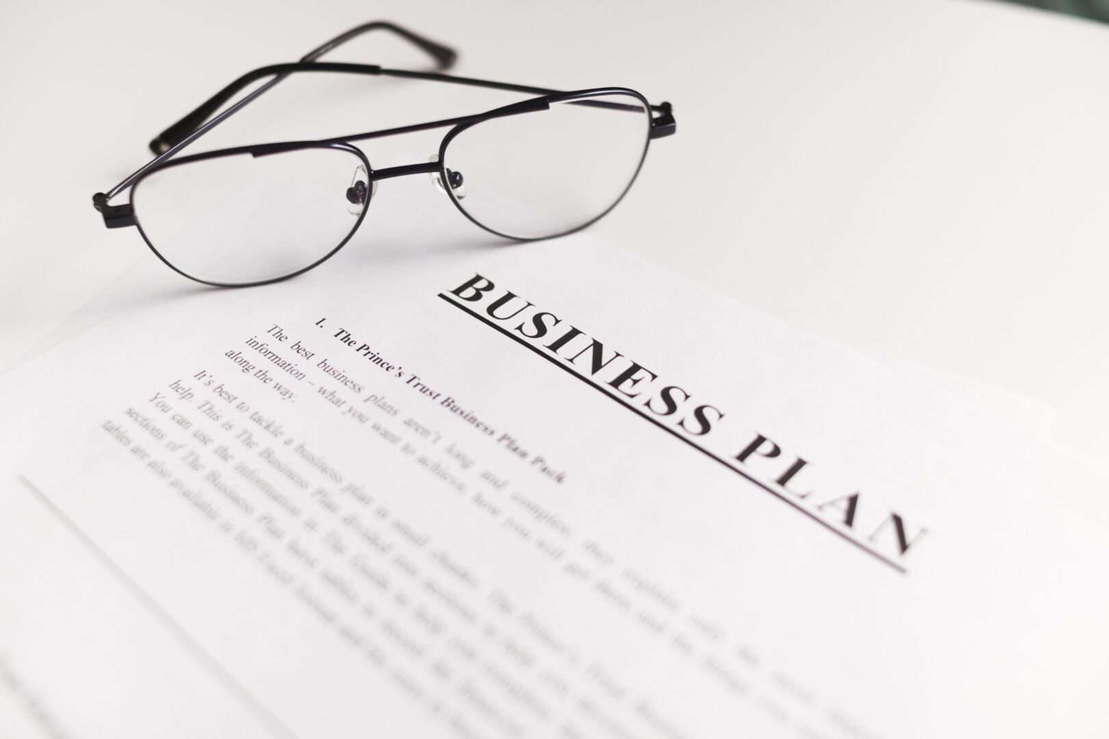 A business plan document with aviator glasses resting on top, representing the strategic legal planning and affordable monthly attorney plans that Carbon Law Group offers to California small business owners.