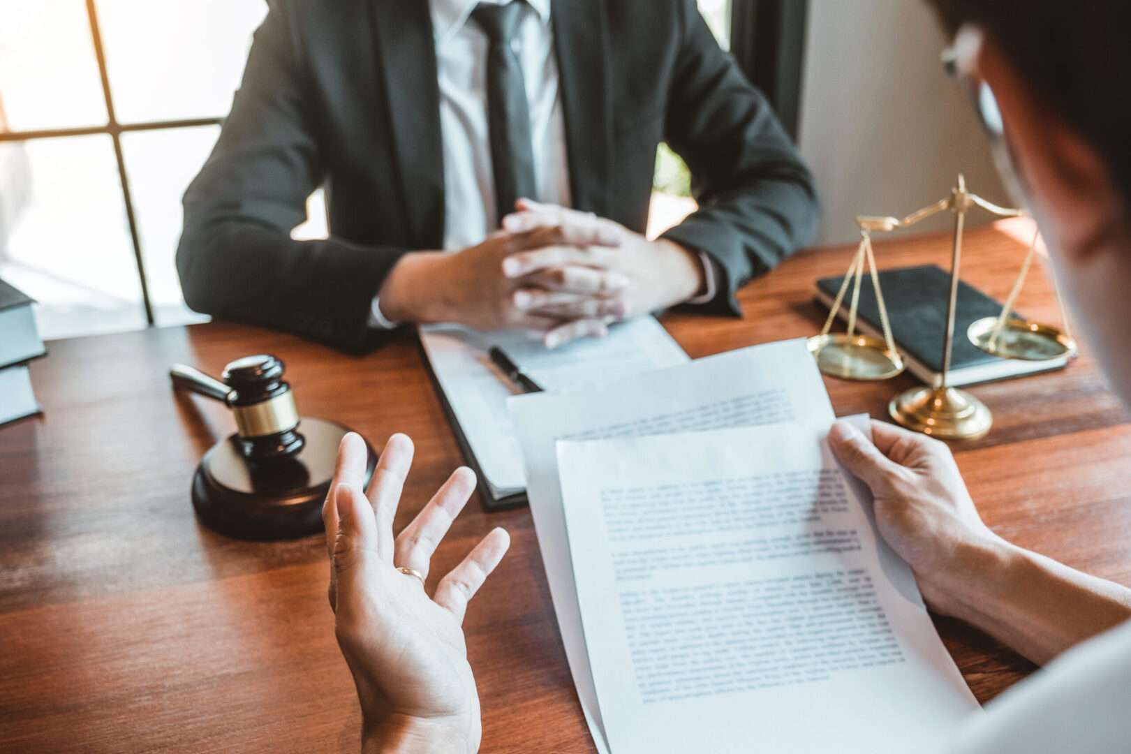 Attorney and business owner reviewing loan documents across a desk, discussing SBA loan requirements for a California LLC