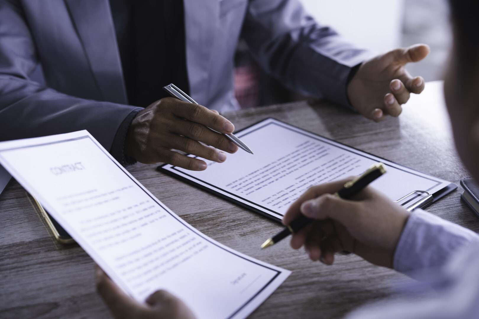 Two people reviewing contract documents across a desk while discussing terms before signing