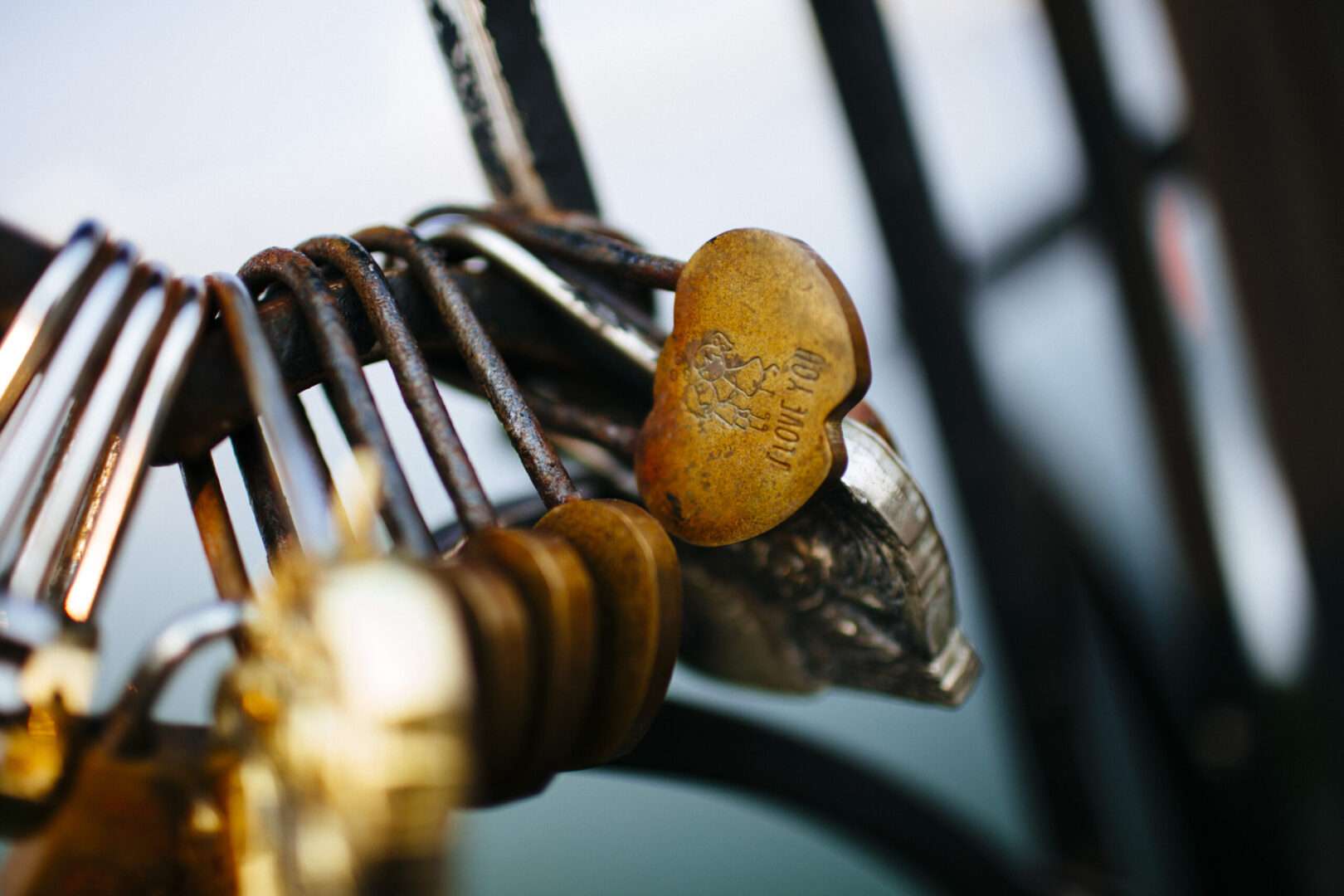 Multiple love locks attached to a bridge railing, including a heart-shaped golden lock engraved with I Love You, representing business partnerships and the legal importance of protecting LLC agreements in Los Angeles