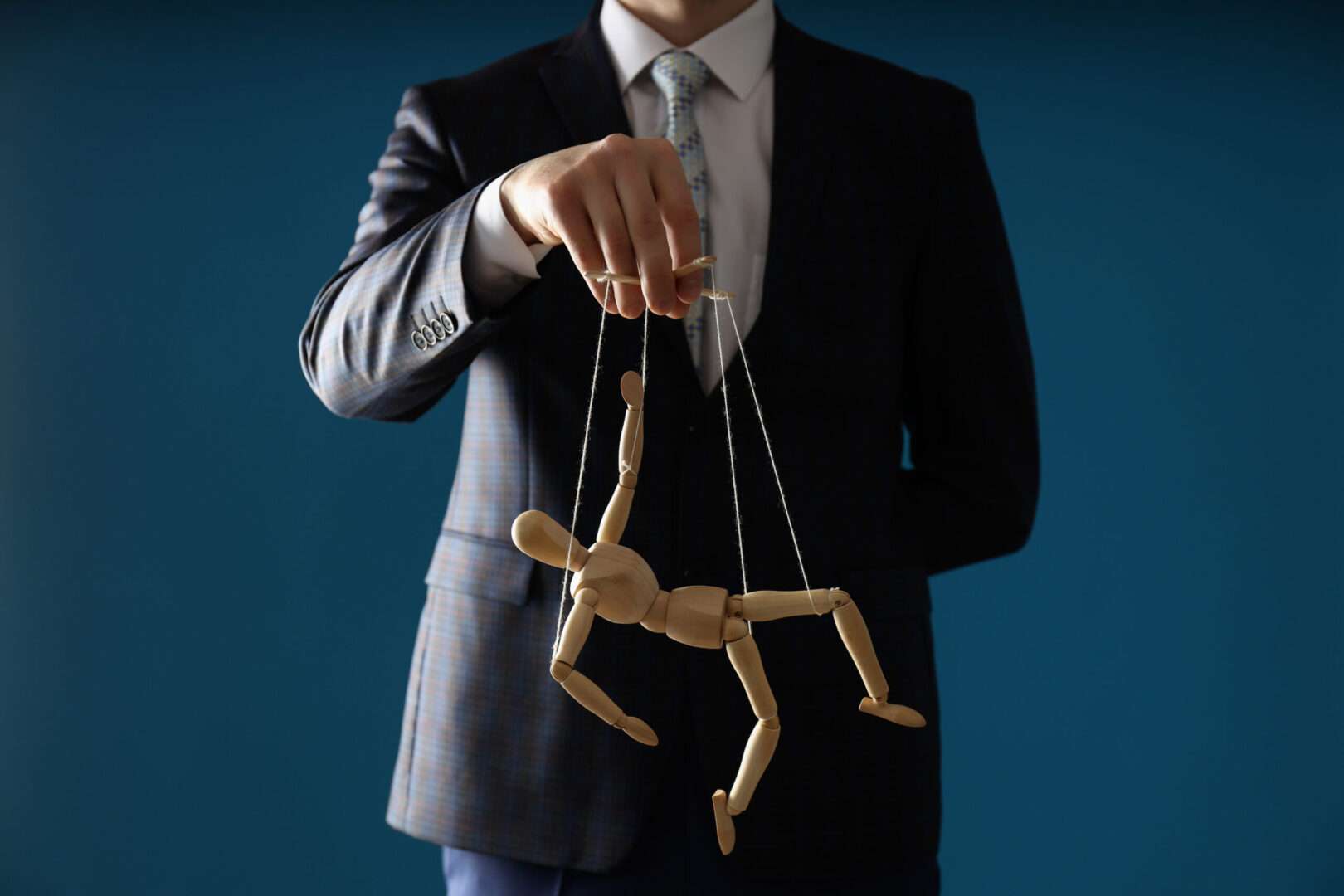Businessman in a suit controlling a wooden marionette on strings, representing unauthorized use of a person's voice and likeness