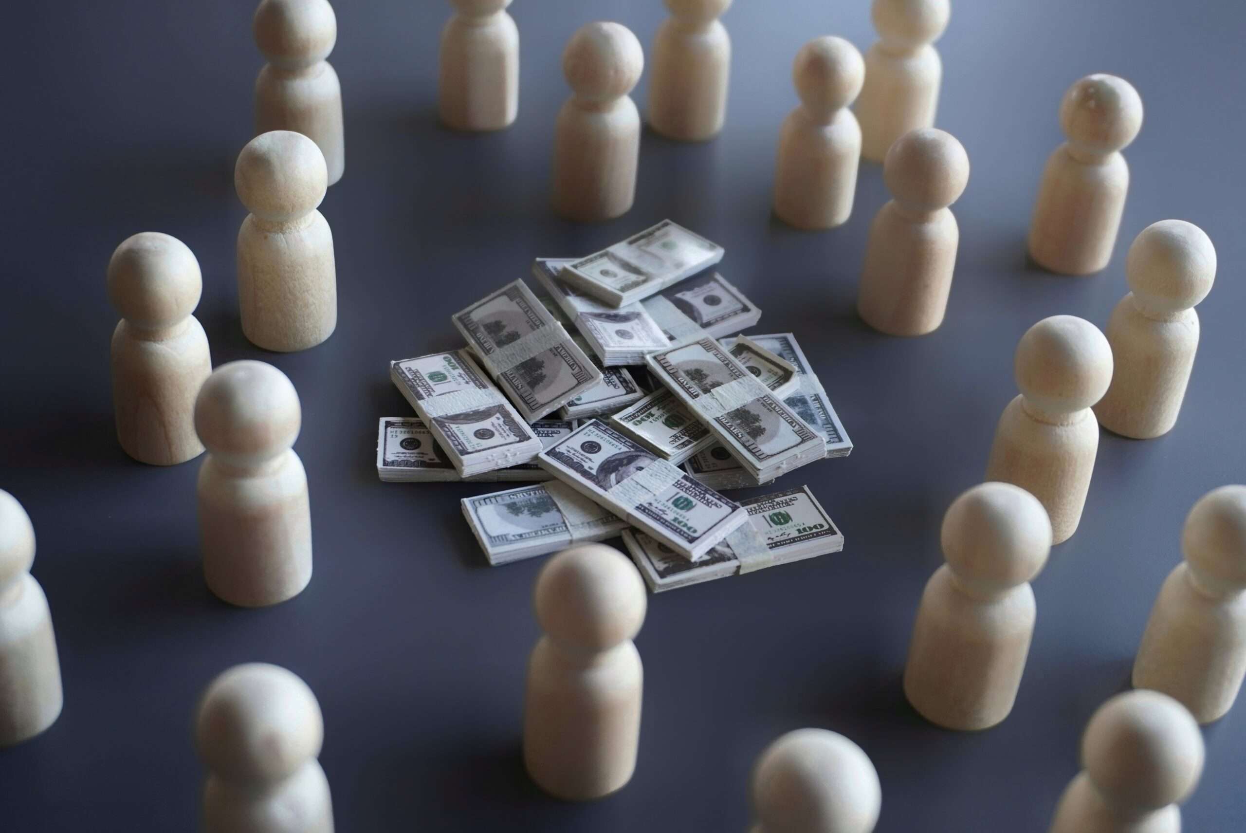 Wooden figures arranged in a circle around stacks of cash, representing investors and lenders with claims on a company's capital