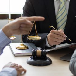 Legal consultation with scales of justice and gavel on table, attorneys discussing contract issues, Los Angeles business law setting.