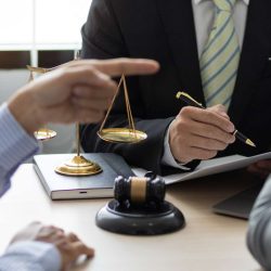 Legal consultation with scales of justice and gavel on table, attorneys discussing contract issues, Los Angeles business law setting.