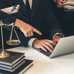 Business attorneys reviewing employment contracts on a laptop during a business acquisition.